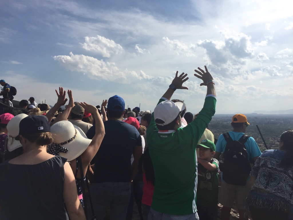 Tourists feel the energy of the sun at the pyramid of the sun in teotihuacan.