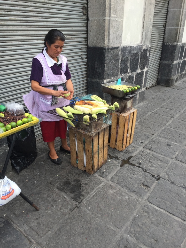 A woman prepares corn on a street in Mexico City.