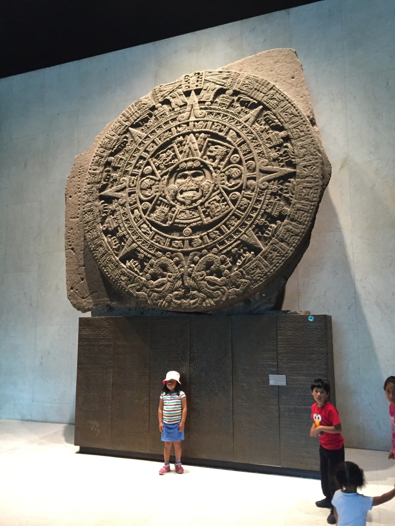 Children pose for photos in front of the Aztec calendar in the Anthropology Museum of Mexico City.
