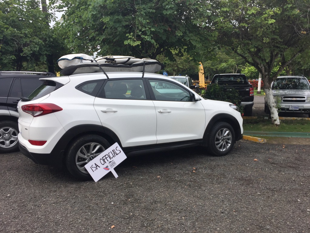 A white SUV sits parked with surfboards strapped on the roof in Costa Rica.