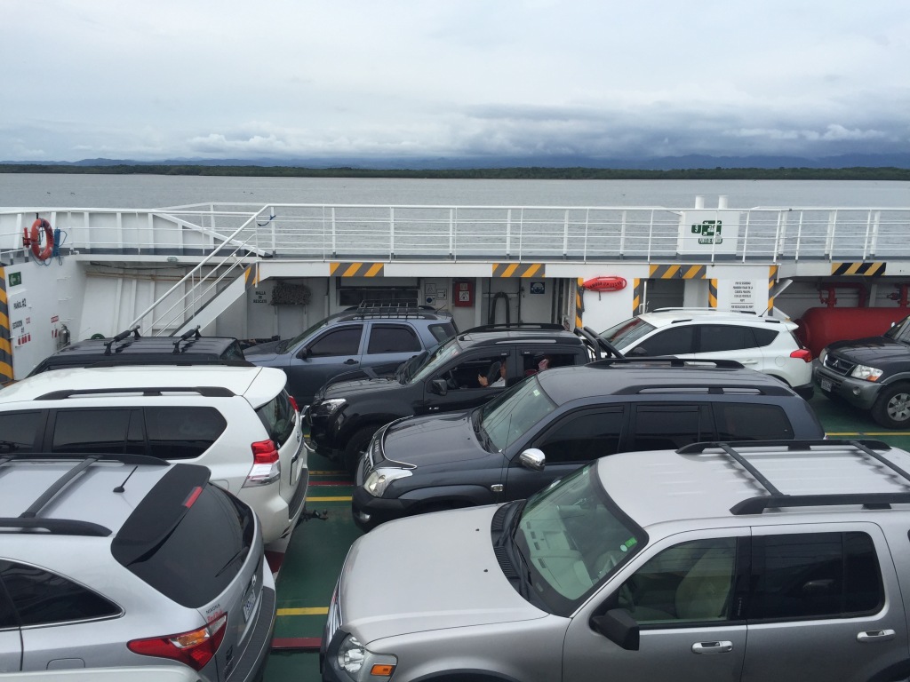 Cars wait on a ferry sailing across a waterway in Costa Rica.